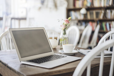 Laptop und Tasse Kaffee auf einem Tisch in einem Café - KNSF000240