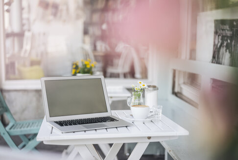 Laptop und Tasse Kaffee auf einem Tisch in einem Café - KNSF000241