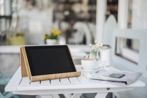 Digitales Tablet, Mobiltelefon, Zeitung und Tasse Kaffee auf einem Tisch in einem Cafe - KNSF000242