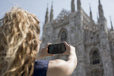 Italien, Mailand, Rückansicht eines Touristen, der die Kathedrale mit dem Mobiltelefon fotografiert - MAUF000798