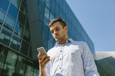 Porträt eines Geschäftsmannes mit Blick auf sein Handy - BOYF000509