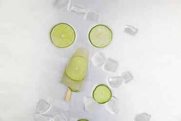 Lime ice lolly, ice cubes and slices of lime on metal - GWF004865