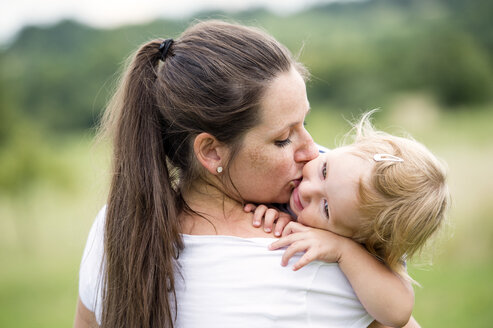 Mutter, die ihre kleine Tochter küsst und umarmt - HAPF000721