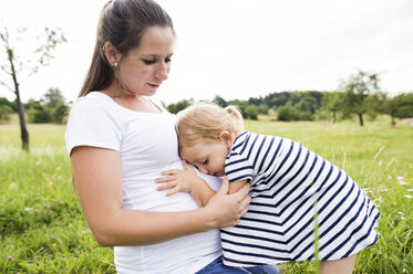 Kleines Mädchen umarmt den Bauch der schwangeren Mutter - HAPF000729