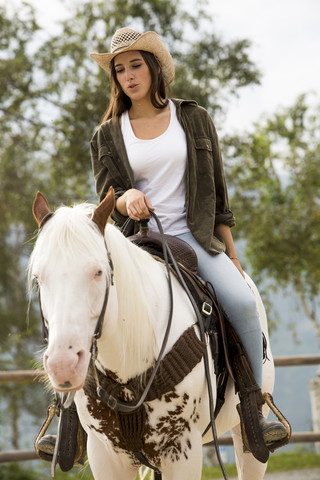 Young woman riding horse at riding stable stock photo