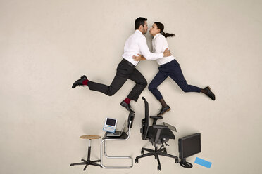 Zwei Kolleginnen balancieren auf Stühlen und küssen sich - BAEF001084