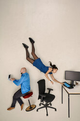 Business woman flying towards office desk, male colleague sitting and working - BAEF001103