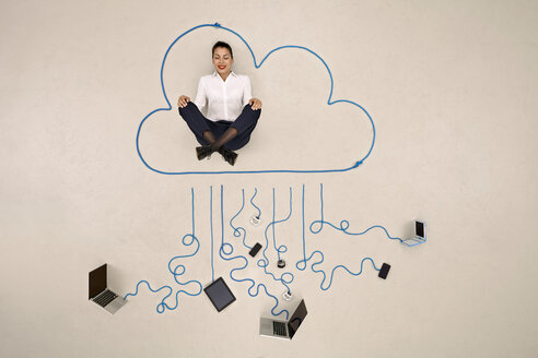 Businesswoman meditating in a cloud connected to mobile devices - BAEF001111