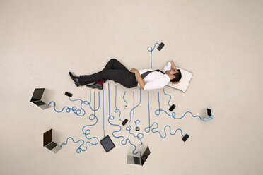 Businessman sleeping connected to mobile devices - BAEF001117