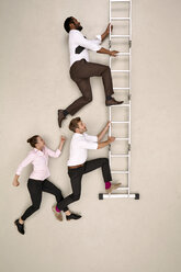 Drei Geschäftskollegen klettern die Leiter hinauf - BAEF001220