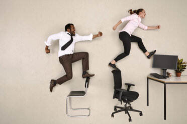 Business colleagues walking on chairs towards office desk - BAEF001229