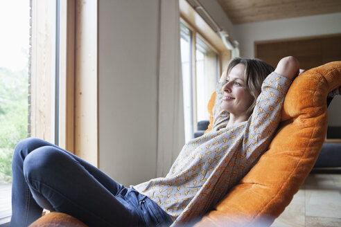 Smiling woman relaxing in armchair - RBF004841