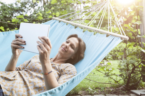 Lächelnde Frau mit digitalem Tablet in der Hängematte, lizenzfreies Stockfoto