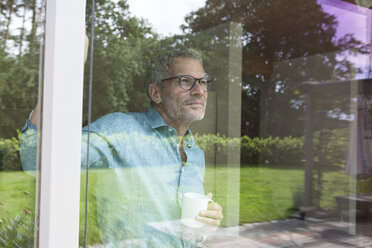 Älterer Mann hält Tasse und schaut aus dem Fenster - RBF004853