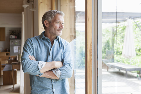 Älterer Mann schaut aus dem Fenster, lizenzfreies Stockfoto