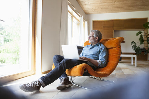 Älterer Mann mit Laptop im Sessel - RBF004861