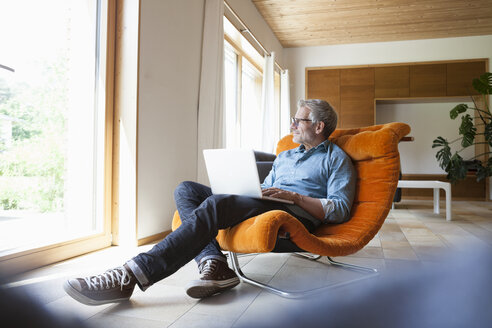 Mature man using laptop in armchair - RBF004861