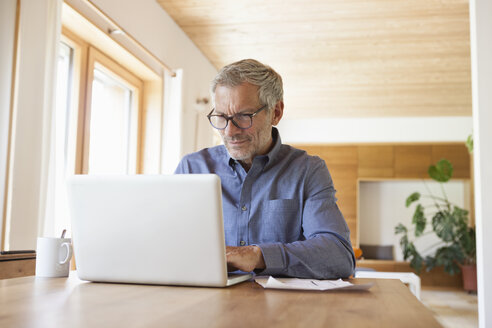 Älterer Mann benutzt Laptop auf Tisch zu Hause - RBF004862
