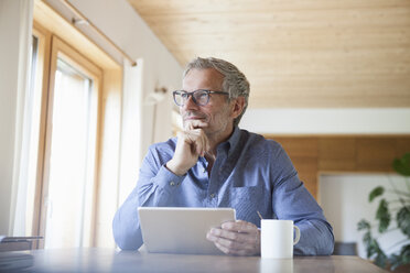 Mature man using digital tablet on table at home - RBF004864