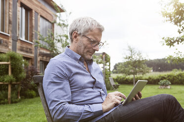 Älterer Mann benutzt digitales Tablet im Garten - RBF004870