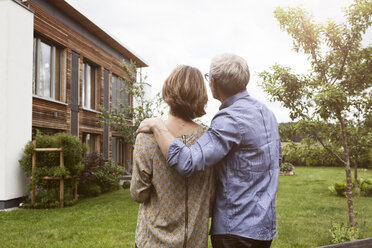 Mature couple in garden looking at house - RBF004877