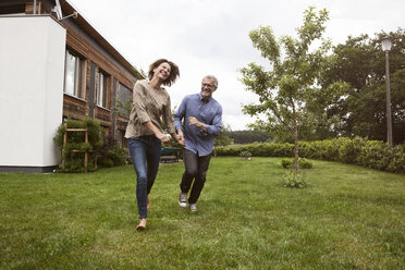 Glückliches reifes Paar läuft im Garten - RBF004878