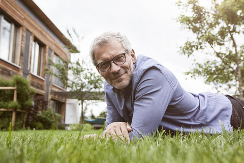 Portrait of smiling mature man lying in garden stock photo