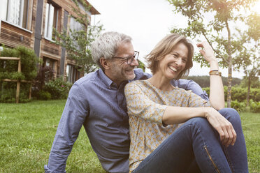 Happy mature couple sitting in garden - RBF004881