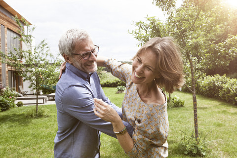 Happy mature couple dancing in garden stock photo