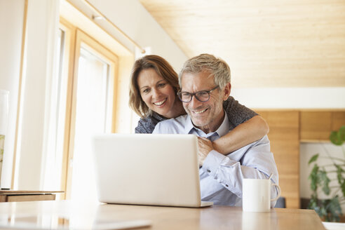 Happy mature couple sharing laptop at home - RBF004894