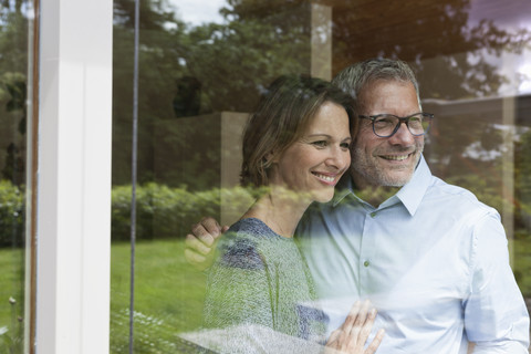 Lächelndes reifes Paar schaut aus dem Fenster, lizenzfreies Stockfoto