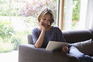 Frau benutzt digitales Tablet auf Couch - RBF004910