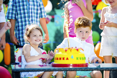 Kleines Mädchen und kleiner Junge feiern Geburtstag im Garten mit Freunden und Familie - HAPF000741