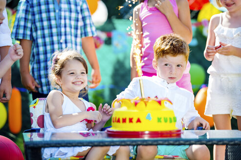 Kleines Mädchen und kleiner Junge feiern Geburtstag im Garten mit Freunden und Familie - HAPF000741
