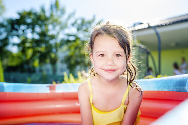 Portrait of smiling little girl sitting in paddling pool - HAPF000758