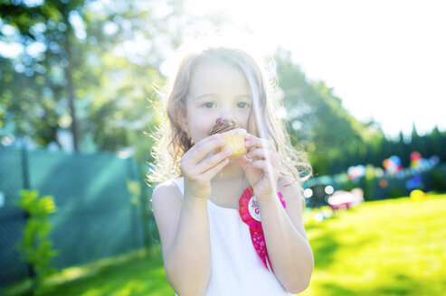 Little girl eating muffin in the garden - HAPF000763