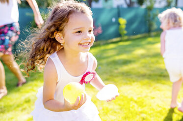 Kleines Mädchen hat Spaß mit Wasserbomben im Garten - HAPF000765