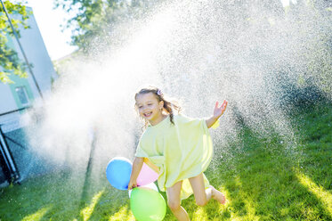 Little girl having fun with lawn sprinkler in the garden - HAPF000769