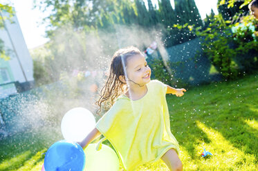 Kleines Mädchen mit Luftballons haben Spaß mit Rasensprenger im Garten - HAPF000772