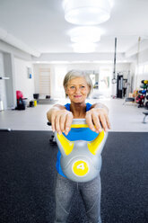 Ältere Frau hebt Kettlebell im Fitnessstudio - HAPF000784
