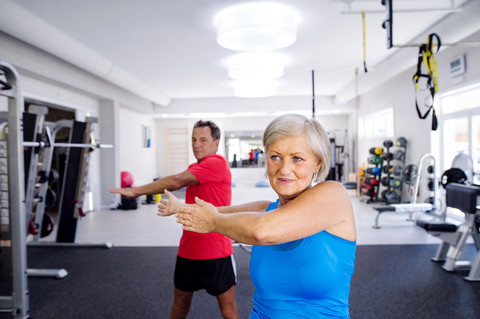 Ältere Frau und älterer Mann machen Gymnastik im Fitnessstudio, lizenzfreies Stockfoto