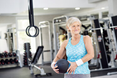 Mature woman holding ball in fitness gym - HAPF000807