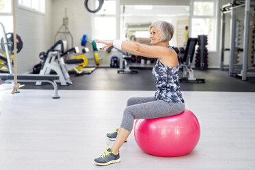 Ältere Frau macht Gymnastik auf Fitness-Ball im Fitnessstudio - HAPF000808