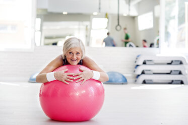 Ältere Frau macht Gymnastik auf Fitness-Ball im Fitnessstudio - HAPF000812