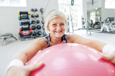Porträt einer lächelnden reifen Frau mit Fitnessball im Fitnessstudio - HAPF000815