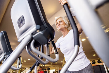 Mature woman exercising on step machine in fitness gym - HAPF000821