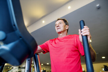 Senior man exercising on step machine in fitness gym - HAPF000826