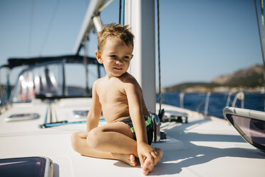 Kleiner Junge sitzt auf dem Bug eines Segelbootes im Sonnenlicht - JRFF000830