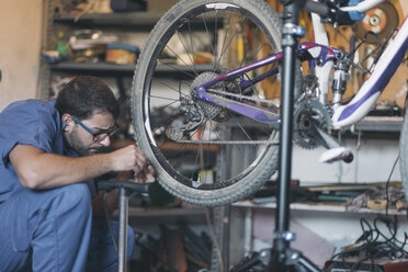 Mechaniker in einer Werkstatt, der ein Fahrrad repariert - SKCF000166