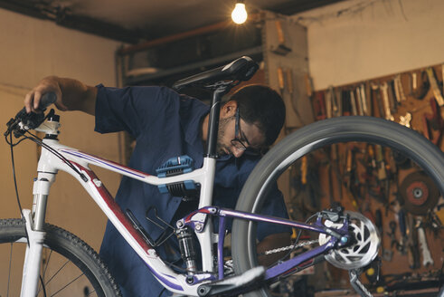 Mechaniker in einer Werkstatt, der ein Fahrrad repariert - SKCF000168